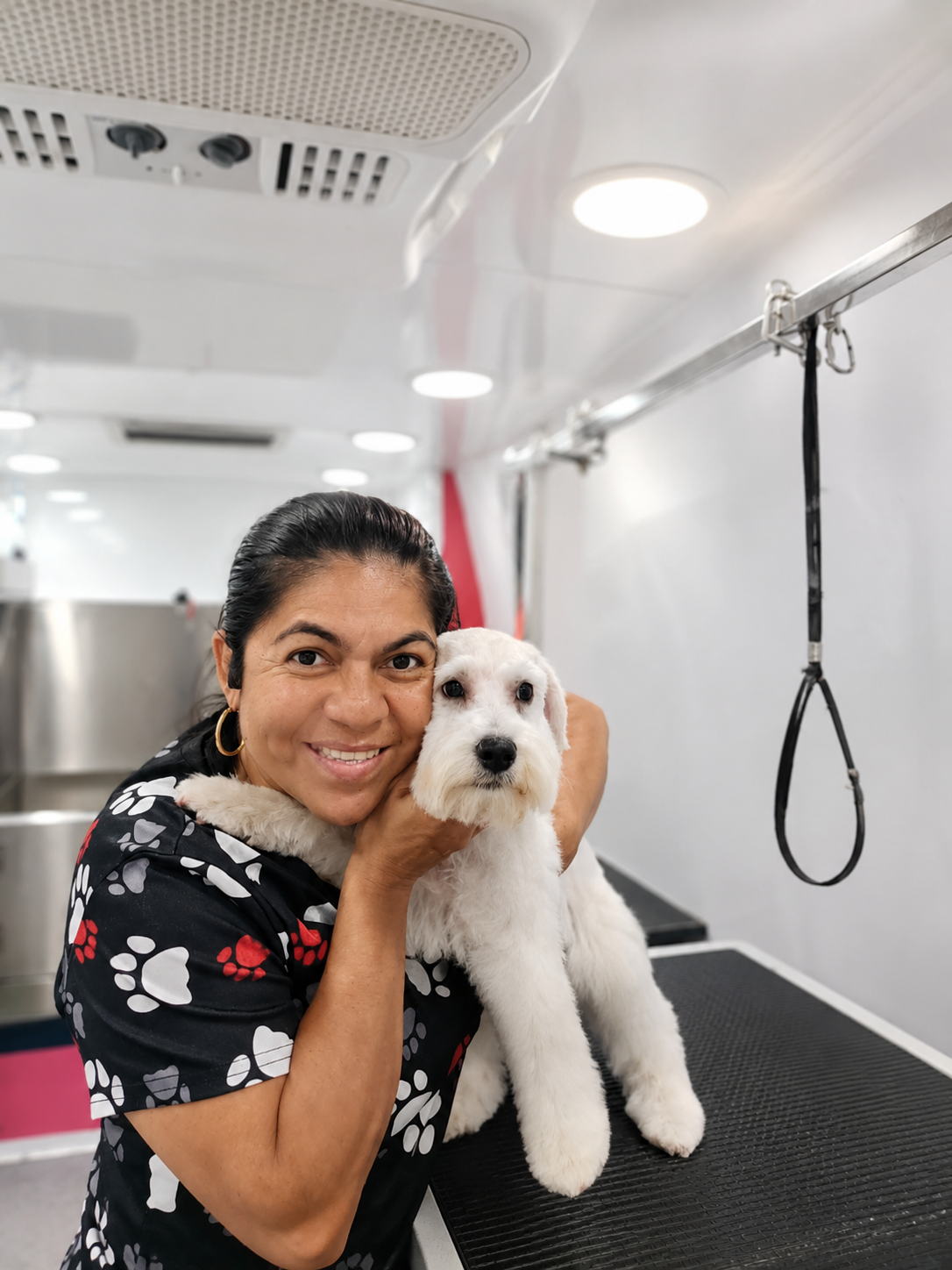Ana Belén holding a freshly groomed white dog inside the Picardia mobile grooming van
